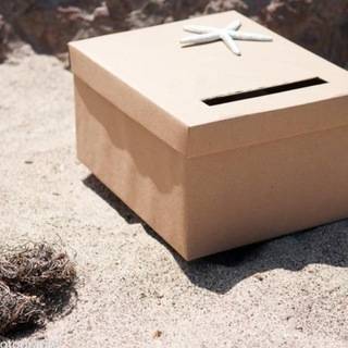 personalized card box wrapped in brown paper and decorated with silver starfish at a beach wedding in Malibu, California