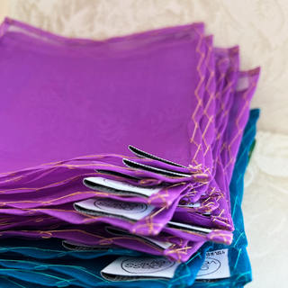 a stack of mulberry silk drink charms in shades of royal purple and peacock blue displayed to show handstitched work 